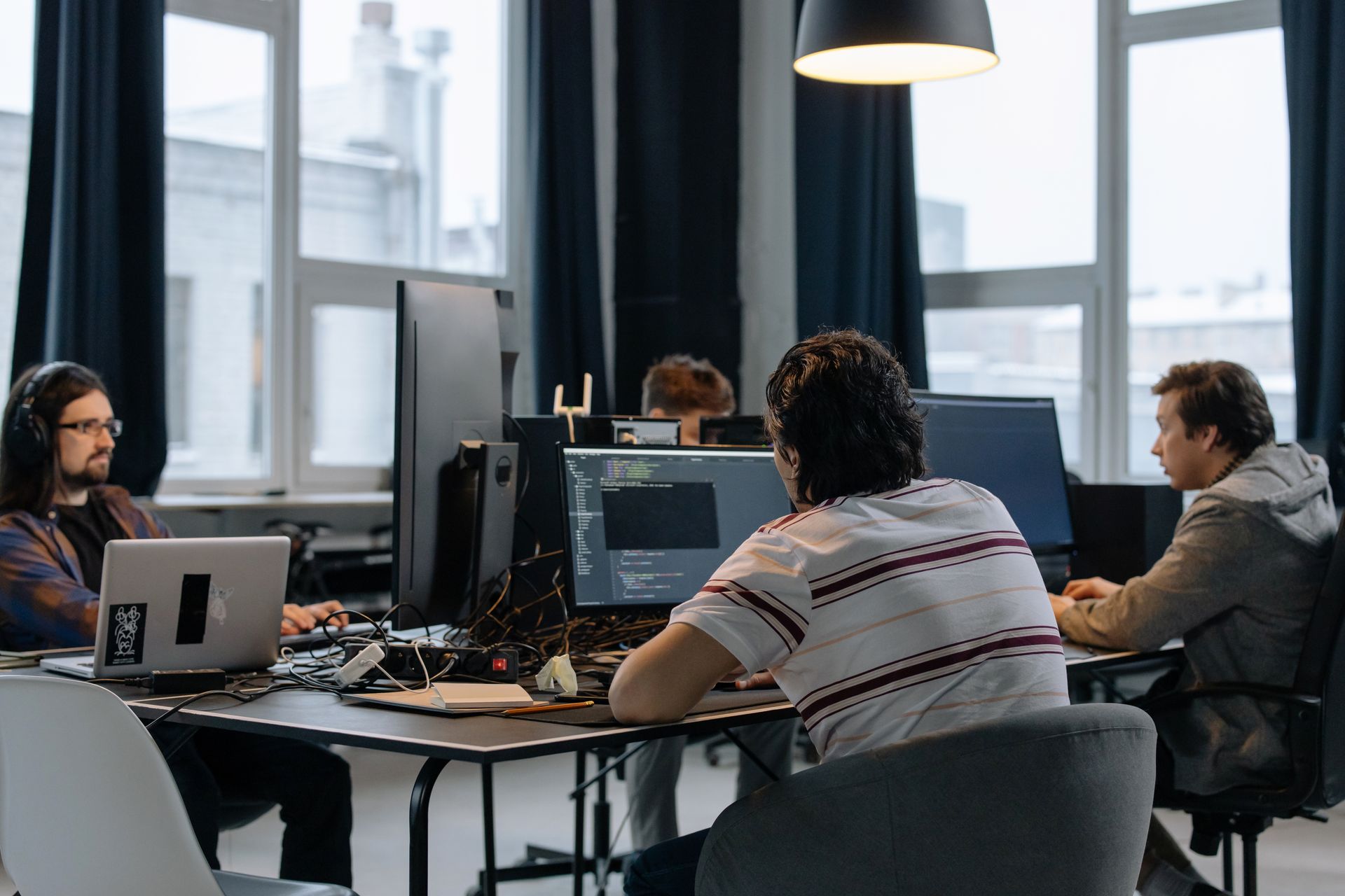 Several people working at desktop computers and laptops in a shared office